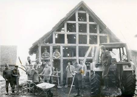 ARH Slg. Bartling 4523, Errichtung eines Fachwerkbaus (Speicher) am Aloys-Bunge-Platz, Blick auf das fertiggestellte und gedeckte Fachwerkskelett von der Giebelseite, davor eine größere Zahl helfender Männer und ein Trecker, Mardorf, zwischen 1989/1990