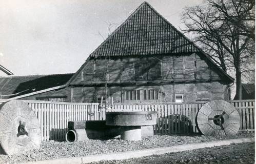 ARH Slg. Bartling 4672, Bauernhaus, Fachwerkbau mit Krüppelwalmdach, mit Ziegeln gedeckt, Giebelansicht, vor dem Bretterzaun an der Straße ein Sitzplatz aus Mühlensteinen mit der Jahreszahl 1974, Niedernstöcken, 1975