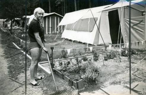 ARH Slg. Bartling 4736, Benachbarter Campingplatz des Freibads im Naherholungsgebiet, jüngere Frau beim Harken vor dem durch Fähnchen abgetrennten Zeltplatz, Nöpke, 1971