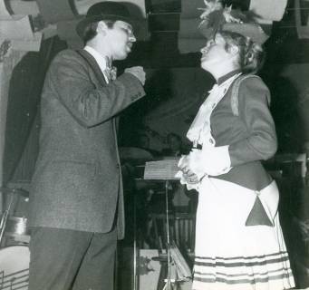 ARH Slg. Bartling 4835, Darsteller mit Hut im Dialog mit einer Darstellerin in Uniform bei einer Theateraufführung im Festzelt, Otternhagen, 1969