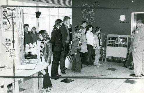 ARH Slg. Bartling 5034, Kinder mit Uniformierten des DRK aufgereiht stehend und auf einen Regalwagen schauend im Vorraum der Schulbücherei, Poggenhagen, 1973