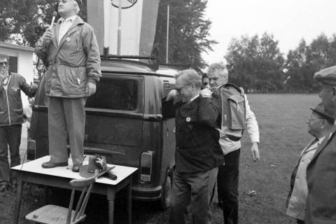 ARH Slg. Weber 02-016/0007, Bürgermeister Helmut Oberheide hält zum Start der Grenzbegehung Gehrdens auf dem Sportplatz des MTV Lemmie eine Rede während Ortsbürgermeister Horst Lanka aus Lemmie einen Rucksack und einen Lederhut erhält, zwischen 1980/1990