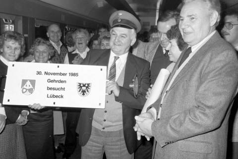 ARH Slg. Weber 02-017/0015, Gehrdens Bürgermeister Helmut Oberheide hält in einem Zugwaggon ein Zuglaufschild anlässlich des Samba-Express "Eine Stadt geht auf Reisen" nach Lübeck, r. Harmonie-Vorsitzender Friedrich Kirchhoff, 1985