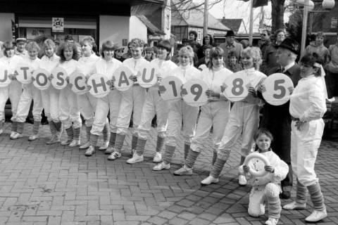 ARH Slg. Weber 02-025/0009, Edeltraud Schultz (rechts) vom Sportverein Gehrden hält mit ihrer Tanz- und Gymnastikgruppe und dem Bürgermeister Helmut Oberheide Schilder für die Autoschau hoch, Gehrden, 1985