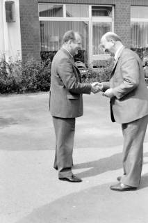 ARH Slg. Weber 02-030/0006, Gehrdens Bürgermeister Gerhard Oberkönig und ein weiterer Mann schütteln sich vor einem Gebäude die Hände, zwischen 1970/1980