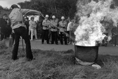 ARH Slg. Weber 02-074/0003, Ein Mitglied der Feuerwehr löscht vor weiteren Mitgliedern einen Brand bei einer Übung, zwischen 1980/1990