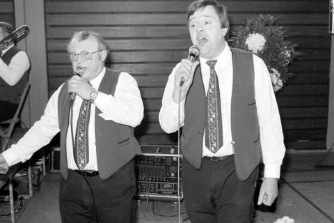 ARH Slg. Weber 02-084/0010, Gesangsauftritt von dem Vorsitzenden Friedrich Eisenberger (links) und Heinz-Dieter Beensen (rechts) beim Frühjahrskonzert des Blasorchesters "Die Original Calenberger", Gehrden, zwischen 1980/1990
