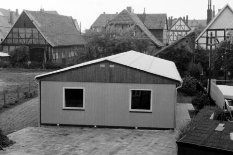 ARH Slg. Weber 02-108/0009, Holzbaracke für die Unterbringung der Bauverwaltung hinter dem Rathaus an der Kirchstraße, im Hintergrund die Fachwerkhäuser an der Neuen Straße, Gehrden, um 1975