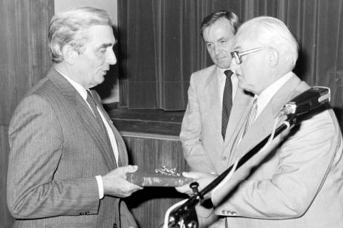 ARH Slg. Weber 02-137/0020, Gehrdens Bürgermeister Helmut Oberheide (rechts) überreicht dem Ratsmitglied Helmut Grefe (CDU) ein Geschenk, dahinter Stadtdirektor Hans Bildhauer, zwischen 1980/1990
