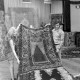 Archiv der Region Hannover, ARH NL Mellin 02-052/0007, Mann und Frau heben einen Teppich von einem Stapel in einem Teppichladen