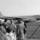 Archiv der Region Hannover, ARH NL Mellin 02-077/0016, Gruppe von Menschen an einem Flughafen, im Hintergrund ein Flugzeug (Typ "Douglas DC-8") der Frachtfluggesellschaft "Airlift International"