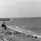 Archiv der Region Hannover, ARH NL Mellin 02-141/0002, Eine Person am Meer sitzend, rechts ein Leuchtfeuer