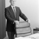 ARH NL Mellin 02-162/0006, Mann hinter seinem Bürostuhl am Schreibtisch stehend