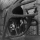 Archiv der Region Hannover, ARH NL Mellin 02-191/0015, Blick durch das Geweih einer Elchskulptur auf ein Ehepaar vor ihrem Bauernhaus