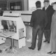 Stadtarchiv Neustadt a. Rbge., ARH Slg. Bartling 408, Drei Männer begutachten den von Einbrechern zerstörten Automaten im Eingangsbereich des Hallenbades