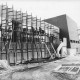 Stadtarchiv Neustadt a. Rbge., ARH Slg. Bartling 411, Bau des Hallenbades, Außenarbeiten mit Gerüst, Ansicht von Süden (Bunsenstraße)