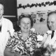 Stadtarchiv Neustadt a. Rbge., ARH Slg. Bartling 680, Marktstraße 1: Ulrich Kollmeyer (links) überreicht einer Frau einen Blumenstrauß im Verkaufsraum, rechts der GF des kl. Supermarktes in der Leinstraße, Neustadt a. Rbge.