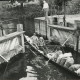 Stadtarchiv Neustadt a. Rbge., ARH Slg. Bartling 1026, Schleusenwärter Ferlemann läßt ein Ruderboot, besetzt mit drei Personen und beladen mit fünf Säcken durch das geöffnete Schleusentor in die Schleuse einfahren, Neustadt a. Rbge.