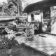 Stadtarchiv Neustadt a. Rbge., ARH Slg. Bartling 1167, Campingplatz am Bannsee, älterer Camper in Freizeitkleidung vor seinem Wochenendhaus auf einer Bank auf der Terrasse am Tisch sitzend, Steinhuder Meer