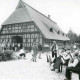 Stadtarchiv Neustadt a. Rbge., ARH Slg. Bartling 1295, Saniertes Bauernhaus "Bargeehr", Ansicht von der Giebelseite des Fachwerkgebäudes, Einweihung mit Blasmusikcombo auf dem Vorplatz, Borstel