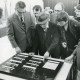 ARH Slg. Bartling 2254, Mehrere Männer beim Betrachten einer auf dem Tisch liegenden Tafel einer Numismatik-Ausstellung im FZZ (2. v. l.: Heinrich Schöneberg), Neustadt a. Rbge.