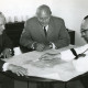 Stadtarchiv Neustadt a. Rbge., ARH Slg. Bartling 2558, Landrat Friedrich Meyer (v. l.), Stadtdirektor Otto Hergt, Dr. Hermann Pfanz, Kali-Chemie, um einen Tisch sitzend und einen Lageplan der Firma Kali-Chemie Pharma studierend