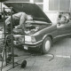 Stadtarchiv Neustadt a. Rbge., ARH Slg. Bartling 2581, Überprüfung der Scheinwerfer eines Fahrzeugs (mit geöffneter Motorhaube) durch zwei junge Männer vor dem Werkstatt Gebäude vom Autohaus A. W. Lange Ford-Händler, Nienburger Straße 1, Neustadt a. Rbge.