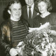 Stadtarchiv Neustadt a. Rbge., ARH Slg. Bartling 2834, Ein Vertreter der Volksbank Neustadt (Mitte) und Monika Zettlitz als Vertreterin der GFW gratulieren einem älteren Mann mit einem Blumenstrauß, Neustadt a. Rbge.