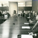 Stadtarchiv Neustadt a. Rbge., ARH Slg. Bartling 3161, Kreiskrankenhaus (später: KRH Klinikum Neustadt a. Rbge.), Lindenstraße 75: Versammlung im Konferenzzimmer unter der Leitung von Kreisdirektor Wolfgang Kunze (stehend rechts), Neustadt a. Rbge.