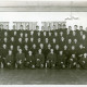 Stadtarchiv Neustadt a. Rbge., ARH Slg. Bartling 3300, Gruppenbild der Mitglieder der Freiwilligen Feuerwehr in Uniform (ohne Mütze) aufgestellt in einem Saal, Ansicht von vorn, Neustadt a. Rbge.