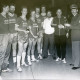 Stadtarchiv Neustadt a. Rbge., ARH Slg. Bartling 3379, Überreichung eines zweiten Pokals an ein Handballteam (in Spielerhemden mit Werbeaufdruck der Firma Reese Öl+Gas) in einer Sporthalle durch einen Polizisten, Neustadt a. Rbge.
