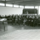 Stadtarchiv Neustadt a. Rbge., ARH Slg. Bartling 3499, Einweihung des Friedhof Lüningsburg, Bürgermeister Fritz Temps am Rednerpult vor den teilnehmenden Gästen in der Aussegnungshalle, Neustadt a. Rbge.
