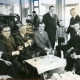 Stadtarchiv Neustadt a. Rbge., ARH Slg. Bartling 3561, Kleine Feier in der Werkhalle der Firma Valentin Reichardt, sechs Herren an einem Tischchen vor den Autos mit einem Glas Sekt und einer Zigarre sitzend, Neustadt a. Rbge.