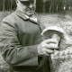 Stadtarchiv Neustadt a. Rbge., ARH Slg. Bartling 3668, Der Meteler Ortsbürgermeister Heinrich Dettmering mit Schirmmütze am Waldrand stehend und einen riesengroßen Steinpilz in der Linken betrachtend, Metel
