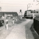 Stadtarchiv Neustadt a. Rbge., ARH Slg. Bartling 4042, Bahnübergang an der Eilveser Hauptstraße, Blick vom Fahrradweg in Richtung Osten auf die geschlossene Schranke und die kreuzende E-Lokomotive, Eilvese