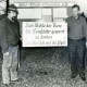 Stadtarchiv Neustadt a. Rbge., ARH Slg. Bartling 4077, Präsentation eines Schildes mit der Aufschrift "Zum Wohle der Tiere für Langläufer gesperrt. Es danken der Ski-Club und die Jäger" durch Hans-Joachim Godau (l.) und Friedrich Duensing, Eilvese