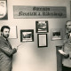 Stadtarchiv Neustadt a. Rbge., ARH Slg. Bartling 4333, Oberstleutnant Streibel (r.) und ein Zivilist vor einer Wand mit historischen Fotos und Wappen sowie einem Wandschild mit dem Schriftzug "Garnison Neustadt a. Rübernberge" stehend, Luttmersen