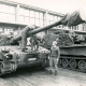 Stadtarchiv Neustadt a. Rbge., ARH Slg. Bartling 4353, Zwei Soldaten bei Wartungsarbeiten an zwei Panzern vor einer Halle, Luttmersen