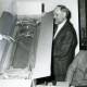 Stadtarchiv Neustadt a. Rbge., ARH Slg. Bartling 4605, Überreichung einer im Karton verpackten Wanduhr zur Verabschiedung von Werner Schulze-Lohhof (rechts) vom Maschinenring durch den 1. Vorsitzenden Henry Hasselbring (2. v. r.) und N. N.