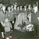 Stadtarchiv Neustadt a. Rbge., ARH Slg. Bartling 4641, Hinter der Erntekrone stehend die Schützen und Schützinnen in Uniform, vorn rechts mehrere Jungen mit Pechfackeln beim Erntefest, Metel