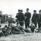 Stadtarchiv Neustadt a. Rbge., ARH Slg. Bartling 4654, Uniformierte Feuerwehrleute in der Pause beim Feuerwehrfest, die Jugend sitzend im Gras, die Erwachsenen stehend dahinter, im Hintergrund ein Löschfahrzeug (LF 16/25), Metel