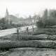 Stadtarchiv Neustadt a. Rbge., ARH Slg. Bartling 4661, Blick von der Landstraße aus Südosten auf die Gorgonius-Kirche, an beiden Seiten der Straße die Stämme von gefällten Eichenbäumen, Niedernstöcken