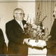 Stadtarchiv Neustadt a. Rbge., ARH Slg. Bartling 4768, Überreichung einer Blumenschale anläßlich der Verabschiedung von Lehrer Heinrich Münchberg (mit Frau) durch Ortsbürgermeister Friedrich Poppe, Otternhagen