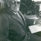 Stadtarchiv Neustadt a. Rbge., ARH Slg. Bartling 4930, Unbekannter älterer Herr aus Scharrel (?) mit getönter Brille, mit Anzug bekleidet, in wohnlicher Umgebung sitzend, mit einem Schriftstück in der Linken, Scharrel